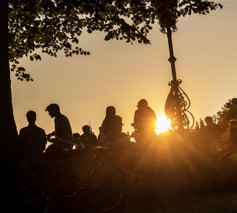Silhouette von Menschen im Park vor einem Sonnenuntergang | © IMAGO / Wolfgang Maria Weber 