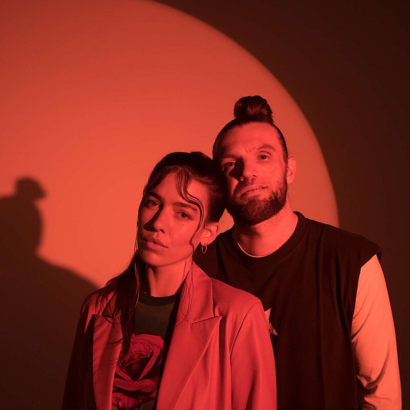 Alina Süggeler und  Andi Weizel von Frida Gold vor rot ausgeleuchtetem Hintergrund. | © Fabian Süggeler