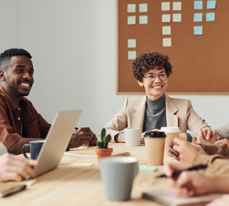 Foto von mehreren Personen in einem Meeting, auf dem Tisch stehen Arbeitsmaterialien und Kaffees  | © Pexels | Fauxels
