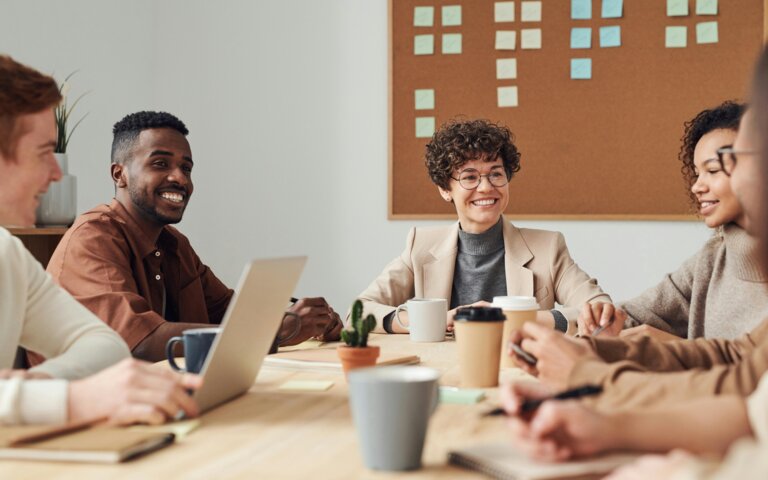 Foto von mehreren Personen in einem Meeting, auf dem Tisch stehen Arbeitsmaterialien und Kaffees  | © Pexels | Fauxels