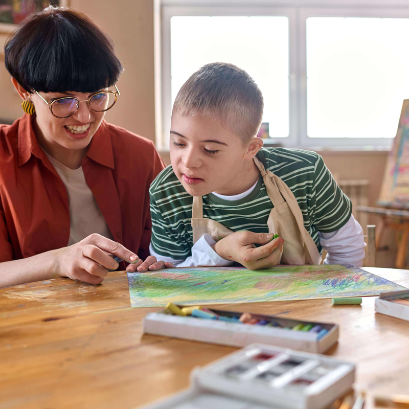 Eine Frau und ein Kind, die gemeinsam an einem Tisch malen.  | © Getty Images | mediaphotos