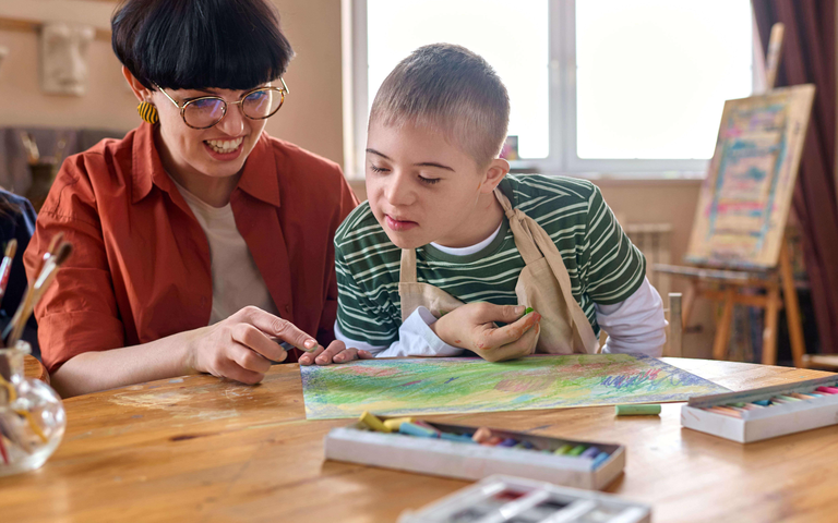 Eine Frau und ein Kind, die gemeinsam an einem Tisch malen.  | © Getty Images | mediaphotos