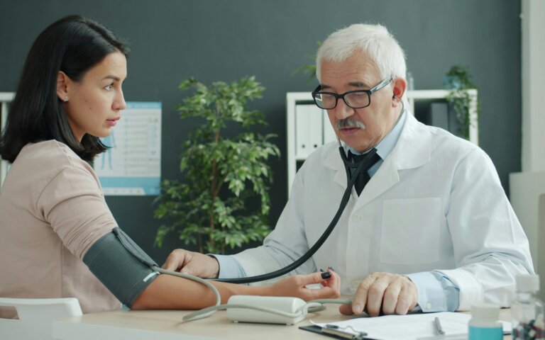 Ein männlicher Arzt misst den Puls einer weiblichen Patietin. | © Vitaly Gariev | Unsplash