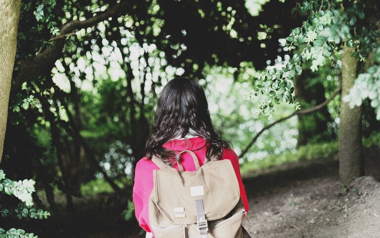 Schulkind mit Rucksack, pinke Jacke, Blick von Kamera weggerichtet.  | © Florencia Viadana | Unsplash 