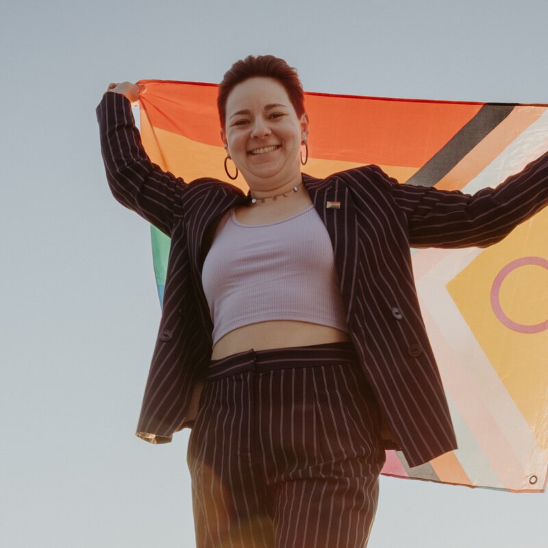 Trauerbegleiterin Caro Zündorf hält eine Pride-Flagge hoch | © Jana Sauer Weddings