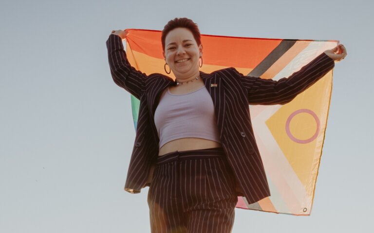 Trauerbegleiterin Caro Zündorf hält eine Pride-Flagge hoch | © Jana Sauer Weddings