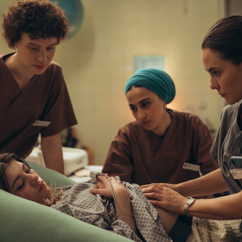 "PUSH - Geheimnisse": Lou (Lisa Moell) liegt in der Klinik. Greta (Lydia Amasko) und Meryem (Tua El-Fawwal) stehen daneben während Dr. Mohn (Katia Fellin) Lou untersucht. | © ZDF | Andrea Hansen: Lou bringt ihr Kind anonym zur Welt. Greta (Lydia Amasko, l.) und Meryem sind für die junge Frau da. Das Kind wird direkt nach der Geburt zur Adoption freigegeben. 