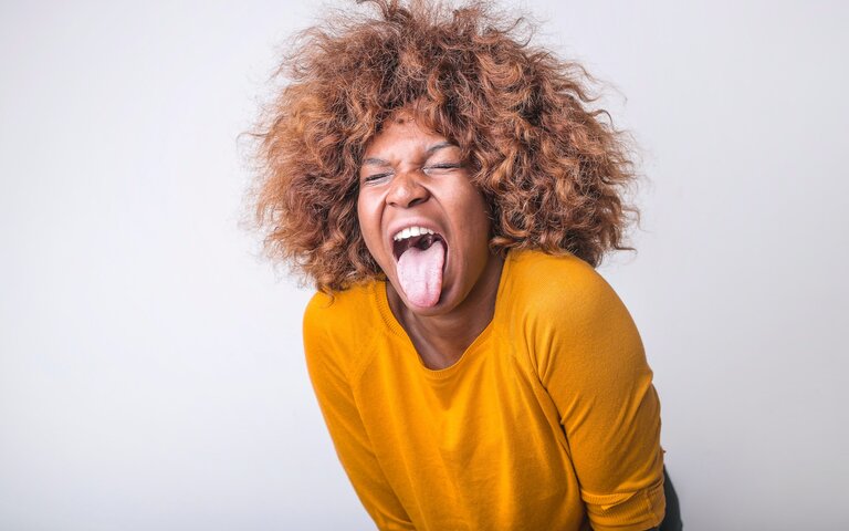 eine Frau in einem gelben Pullover sieht geekelt aus | © Pexels | Andrea Piacquadio