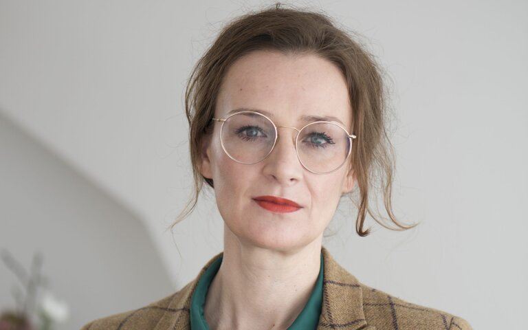 Auf dem Foto ist die Publizistin Franziska Schutzbach zu sehen, sie trägt eine flaschengrüne Bluse und einen karierten Blazer. | © Foto: Anja Fonseka