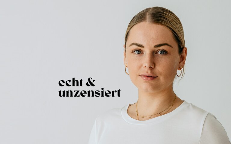 Hebamme Eva Placzek steht vor einer weißen Wand und lächelt. | © Eva Placzek