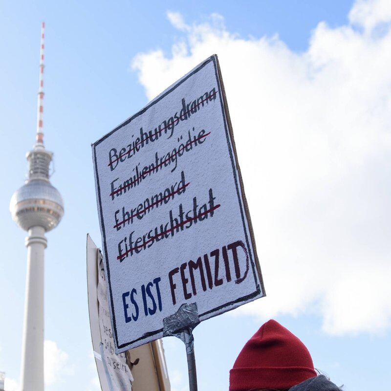 Demonstrationsschild: Es ist Femizid. Hintergrund: Blauter Himmel und Fernsehturm in Berlin | © Foto: Christian Spicker | IMAGO 