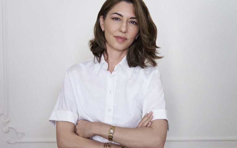Das Bild zeigt die Regisseurin Sofia Coppola vor einer weißen Wand stehend. | © Sofia Coppola hat Priscilla Presleys Geschichte verfilmt. Foto: Melodie McDaniel