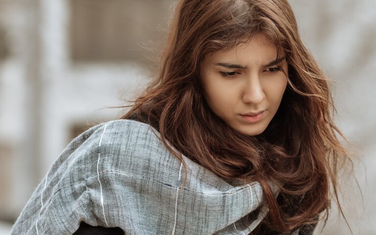 Frau, traurig, an eine Brüstung gelehnt. | © Foto: Omid Armin | Unsplash 